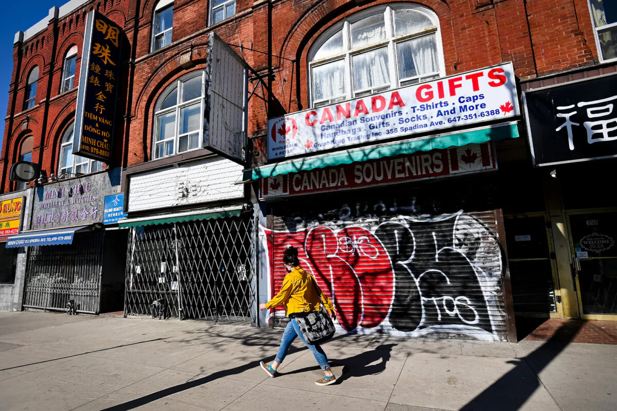 A woman walks past closed businesses on Spadina Avenue in Chinatown in Toronto on May 13, 2021. (The Canadian Press/Nathan Denette)