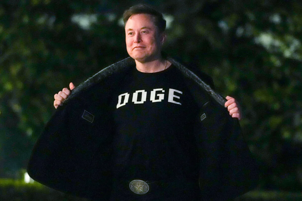 Elon Musk shows off a shirt that says "DOGE" as he walks on the South Lawn of the white House after stepping off Marine One upon arrival to the White House on March 9, 2025. (Oliver Contreras/AFP via Getty Images)