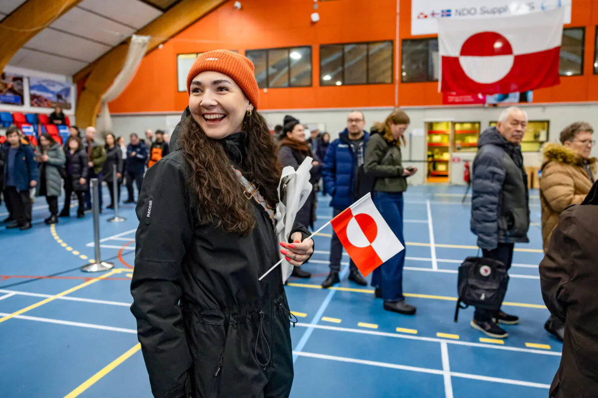 A woman holds a Greenlandic national flag as she queues to vote at the polling station in Nuuk, Greenland, on March 11, 2025. (Odd Andersen/AFP via Getty Images)