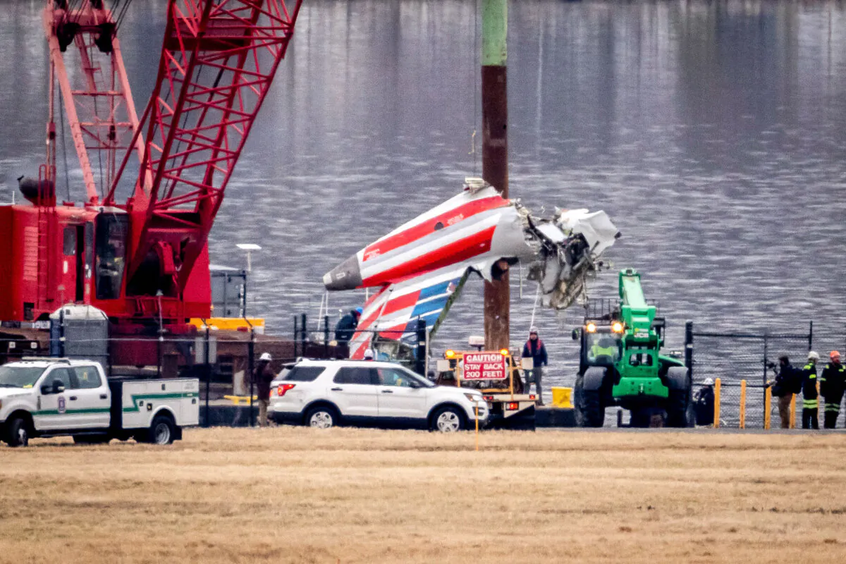 A crane offloads a piece of wreckage from a salvage vessel onto a flatbed truck, near the wreckage site in the Potomac River of a midair collision between an American Airlines jet and a Black Hawk helicopter, at Ronald Reagan Washington National Airport, in Arlington, Va., on Feb. 5, 2025. (Ben Curtis/AP Photo)