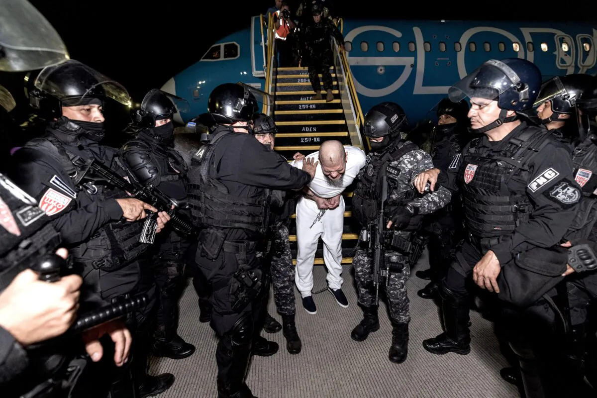 Salvadoran police officers escort alleged members of the Tren de Aragua gang recently deported by the U.S. government to be imprisoned in the Terrorism Confinement Center (CECOT) prison, as part of an agreement with the Salvadoran government, at the San Oscar Arnulfo Romero international airport in San Luis Talpa, El Salvador, on March 16, 2025. (Secretaria de Prensa de la Presidencia/Handout via Reuters)