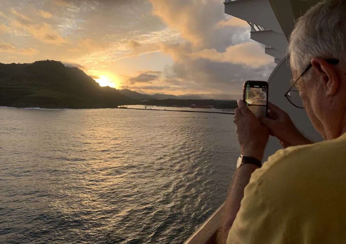 The author's husband, Carl Larsen, captures a Hawaiian sunset off the coast of Kauai. (Sharon Whitley Larsen)