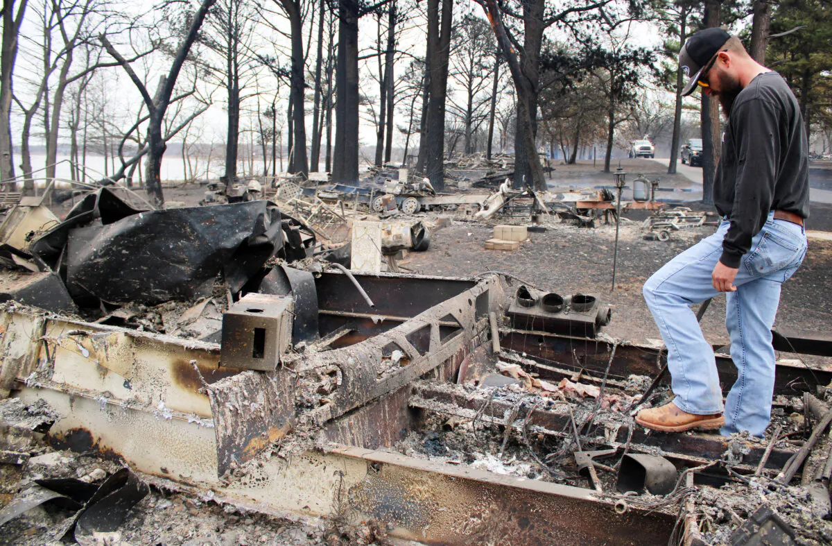 Dacota Roberson looks through the burned wreckage of his parents' camper at Lake Carl Blackwell just outside Stillwater, Okla., on March 15, 2025. (Michael Clements/The Epoch Times)