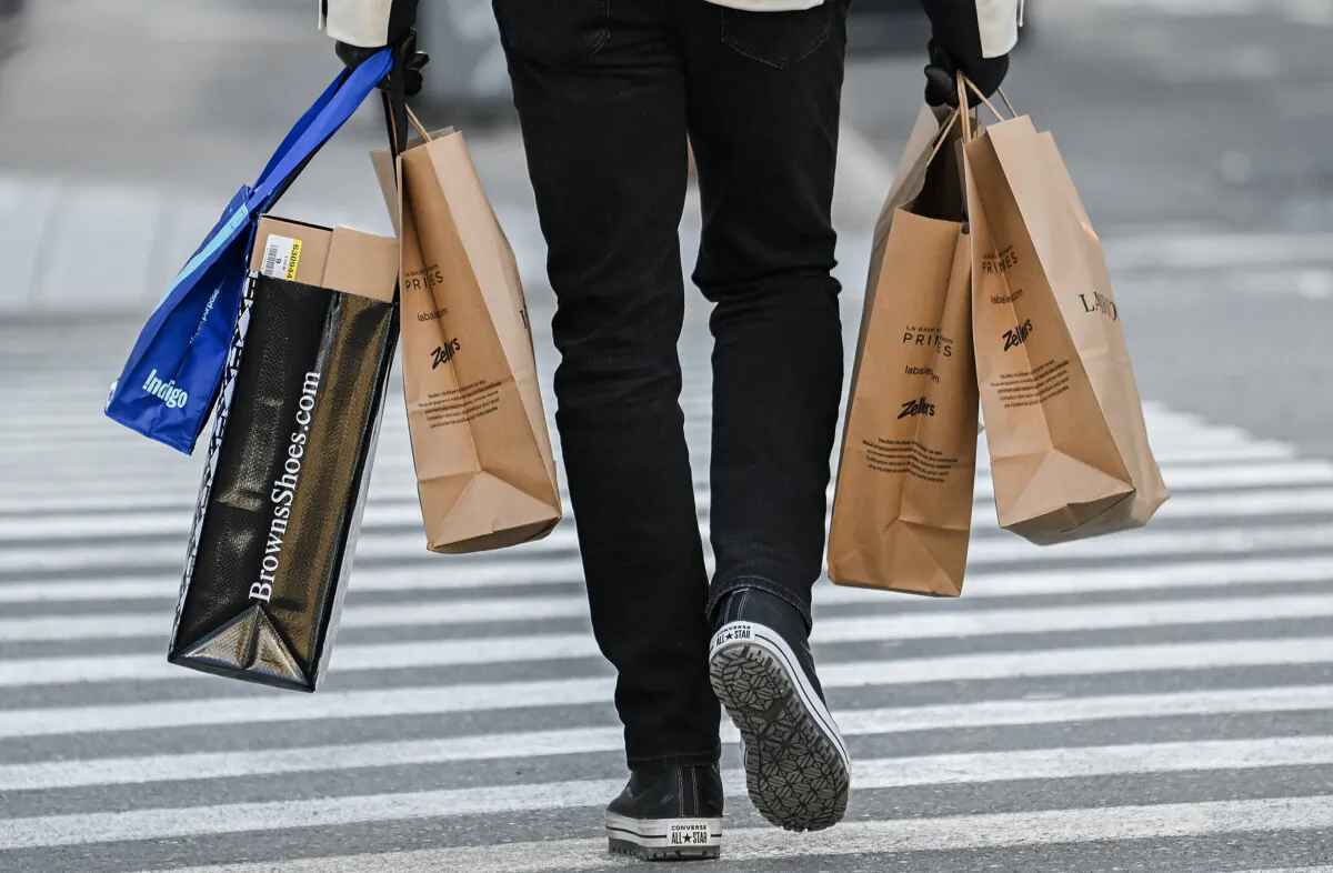 A person carries shopping bags along a street in Montreal, on Dec. 14, 2024. (The Canadian Press/Graham Hughes)