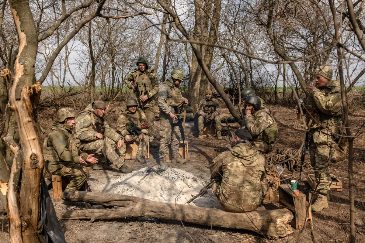 Members of the 24th Mechanized Brigade of the Ukrainian Military rest around a fire after a field training exercise in an undisclosed location in the eastern region of Ukraine, on March 18, 2025, amid the Russian invasion of Ukraine. (Photo by Roman PILIPEY / AFP) (Photo by ROMAN PILIPEY/AFP via Getty Images)