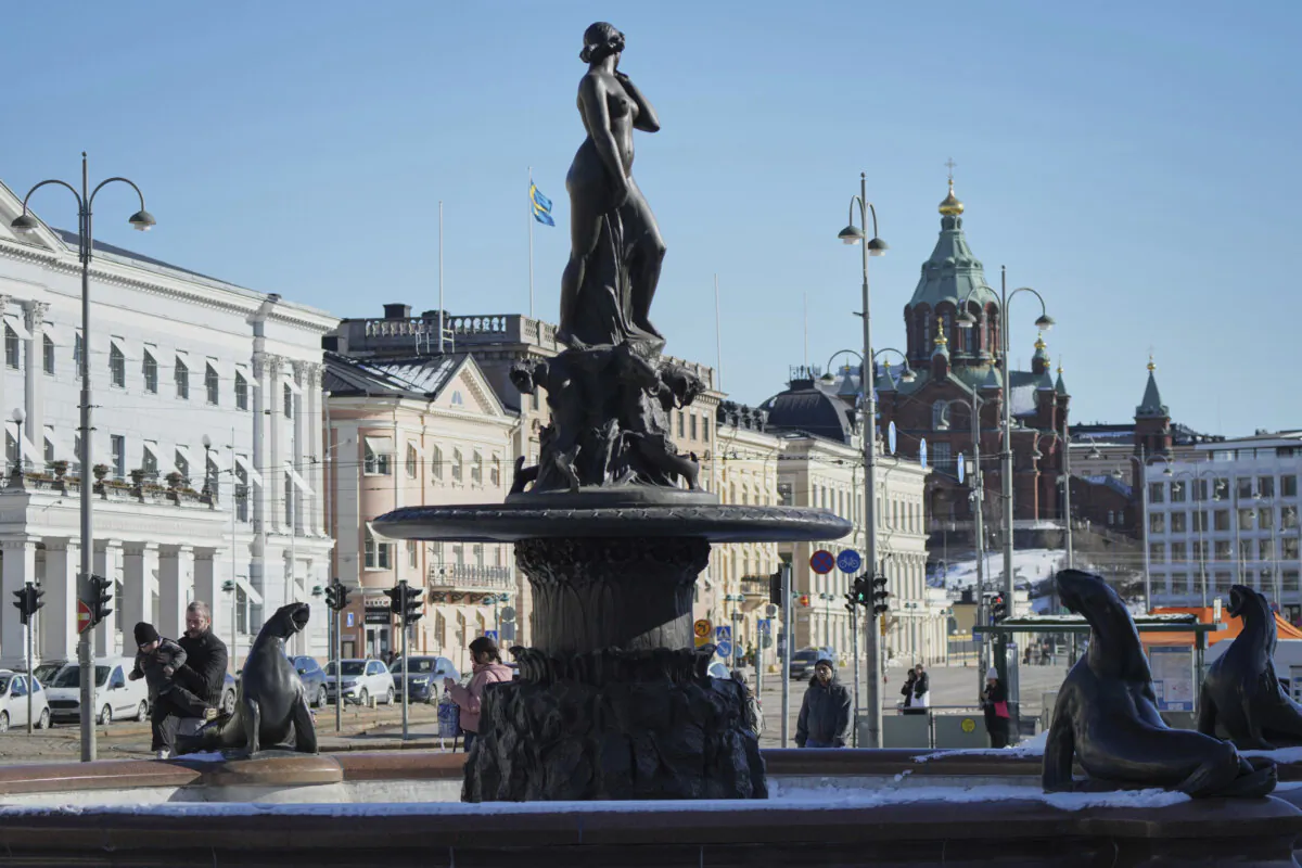 People walk next to the Havis Amanda statue on the Market Square in the center of Helsinki on March 15, 2025. (Sergei Grits/AP Photo)