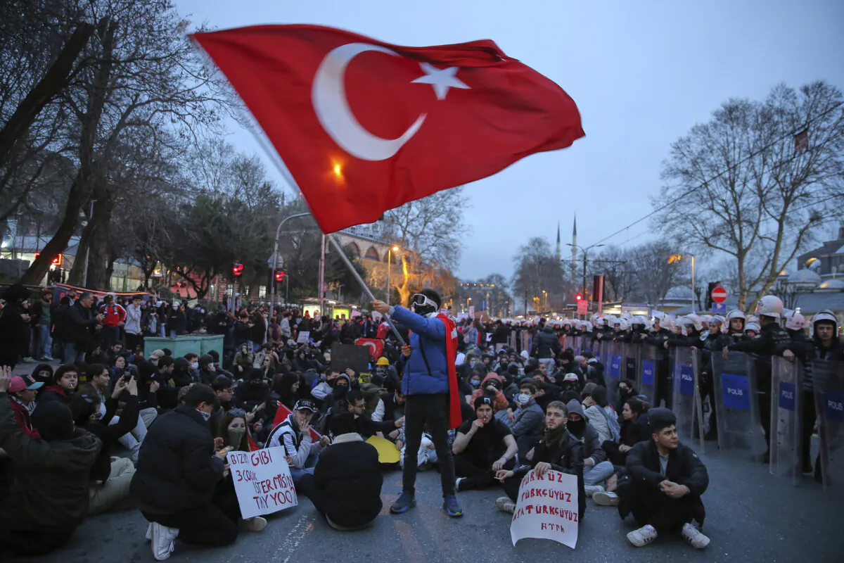 University students sit next to riot police officers during a protest after Istanbul's Mayor Ekrem Imamoglu was arrested and sent to prison, in Istanbul on March 24, 2025. (Huseyin Aldemir/AP)