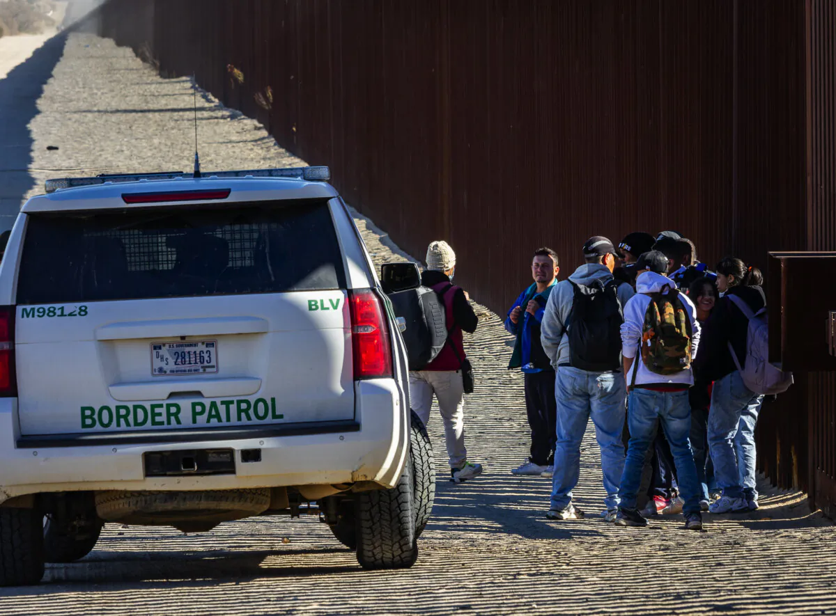 Migrants who illegally crossed into the United States await processing by U.S. Border Patrol agents outside of San Diego, Calif., on Dec. 5, 2023. (John Fredricks/The Epoch Times)