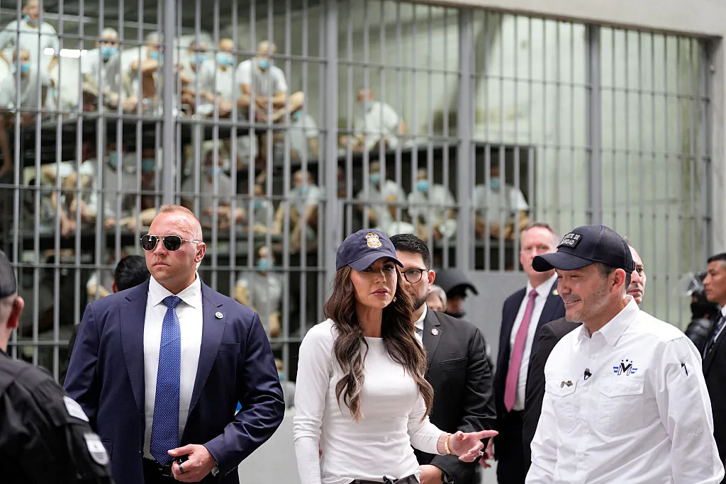 Prisoners watch behind bars as U.S. Secretary of Homeland Security Kristi Noem accompanied by Minister of Justice and Public Security Gustavo Villatoro (R), tours the Terrorist Confinement Center (CECOT) in Tecoluca, El Salvador, on March 26, 2025. (Alex Brandon/Pool/AFP via Getty Images)