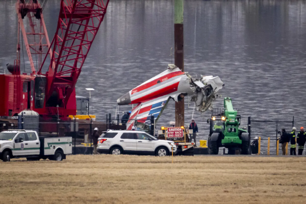 A crane offloads wreckage from a salvage vessel onto a flatbed truck in Arlington, Va., on Feb. 5, 2025, a week after a midair collision between an American Airlines jet and a Black Hawk helicopter over the Potomac River near Ronald Reagan Washington National Airport. (Ben Curtis/AP Photo)