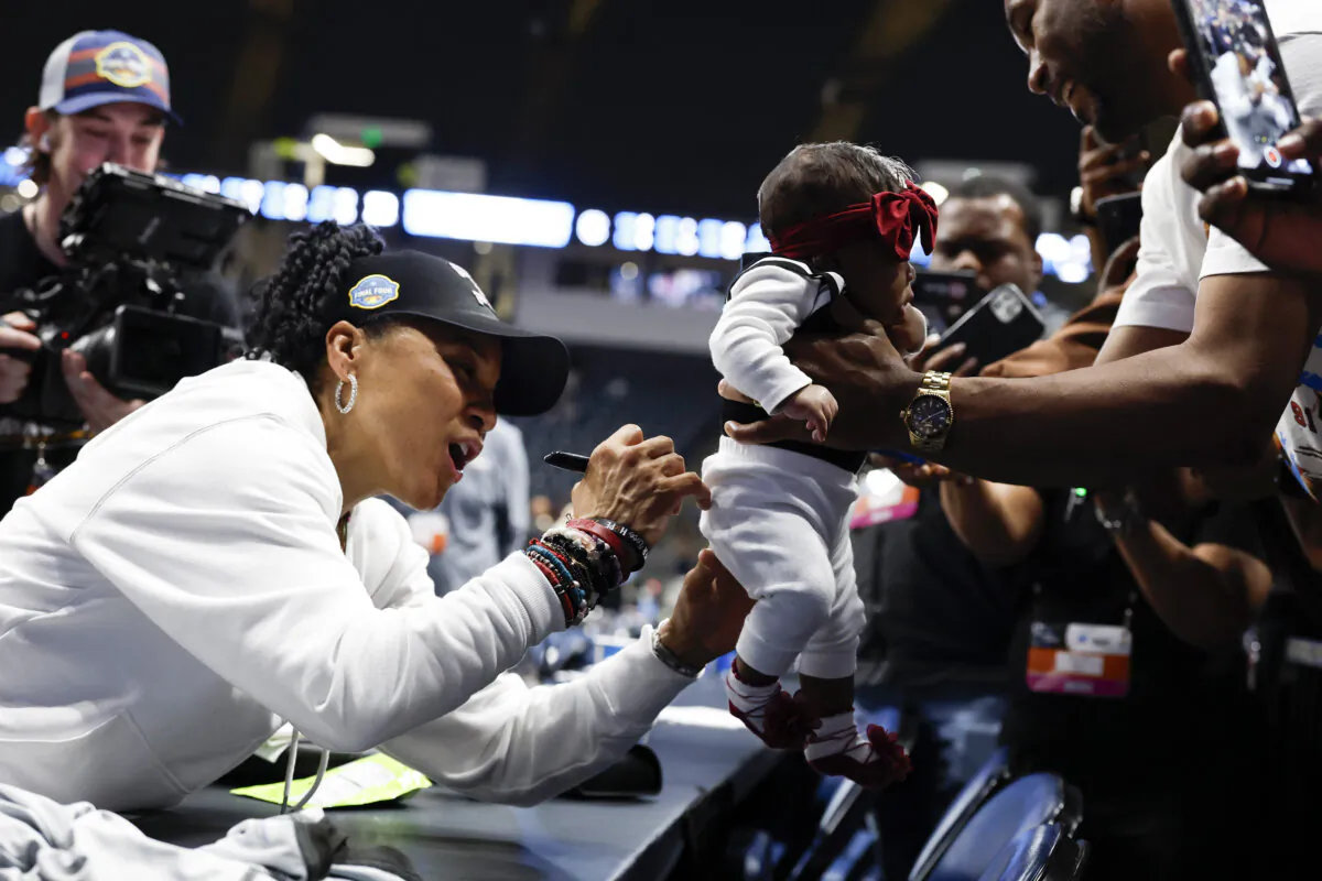 South Carolina head coach Dawn Staley autographs a baby's clothes after defeating Duke in the Elite Eight of the NCAA college basketball tournament to advance to the Final Four in Birmingham, Ala., on March 30, 2025. (Butch Dill/AP Photo)