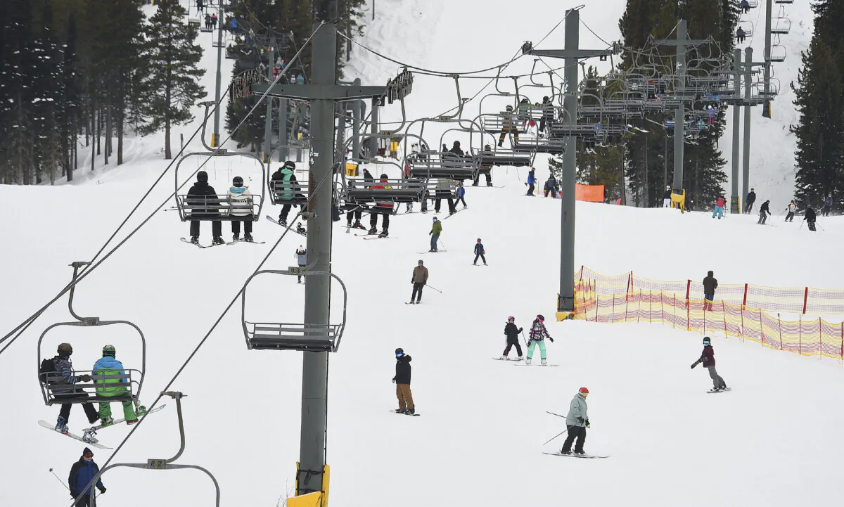 People ride a chairlift as skiers and snowboarders pass below at Red Lodge Mountain, Feb. 20, 2023, near Red Lodge, Mont. (Larry Mayer/The Billings Gazette via AP)
