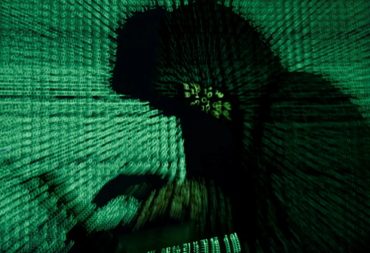 A man holds a laptop computer as cyber code is projected on him in this illustration produced on May 13, 2017. (Kacper Pempel/Illustration/Reuters)