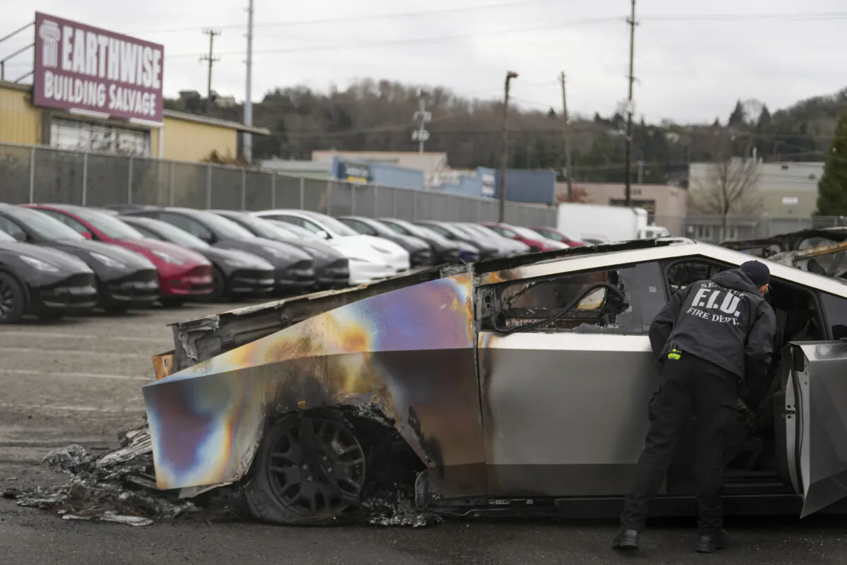 A member of the Seattle Fire Department inspects a burned Tesla Cybertruck at a Tesla lot in Seattle on March 10, 2025. (AP Photo/Lindsey Wasson, File)