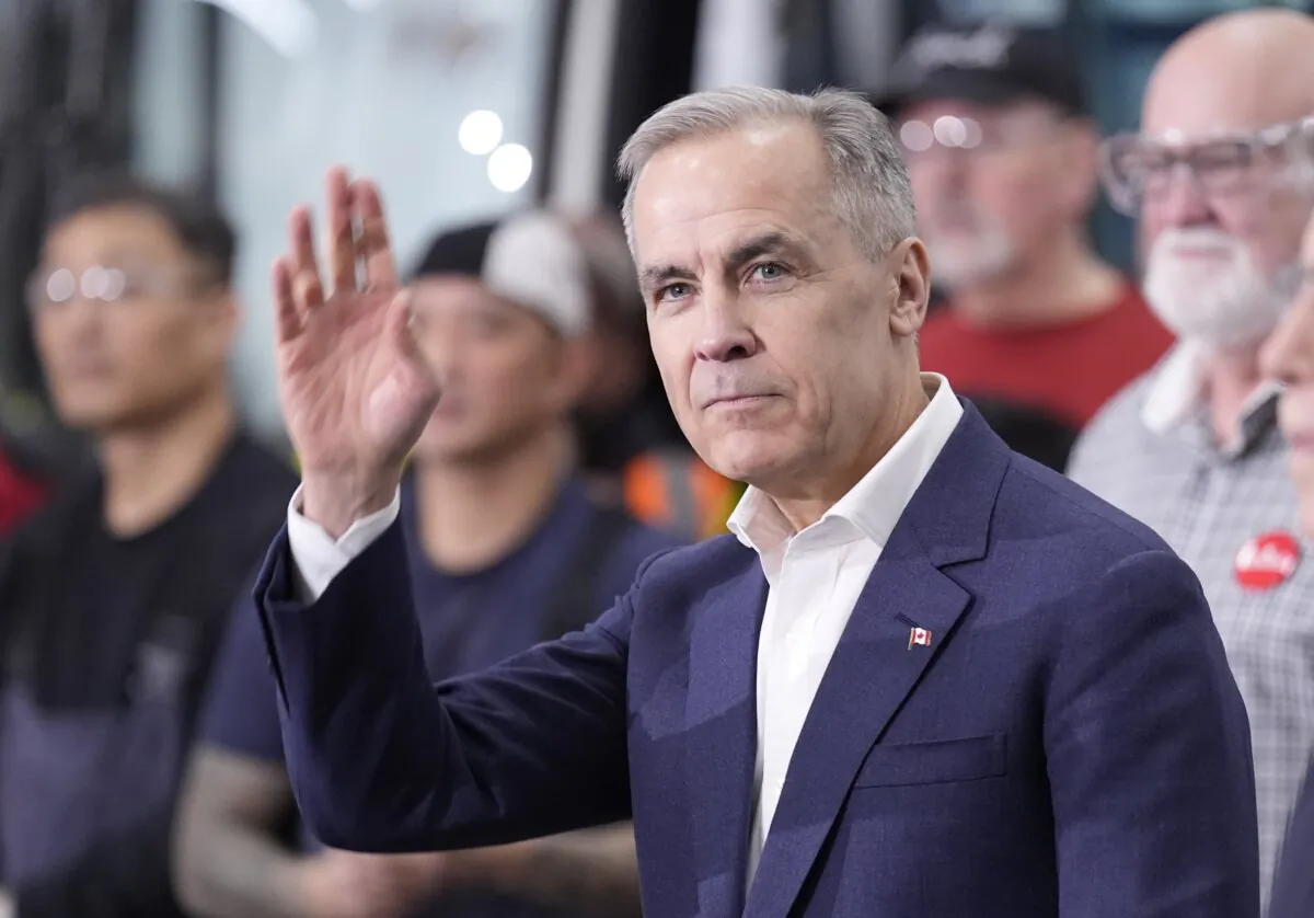 Liberal Leader Mark Carney waves to workers gathered as he makes a campaign stop at a bus factory on Apr. 1, 2025, in Winnipeg. (Adrian Wyld/The Canadian Press)