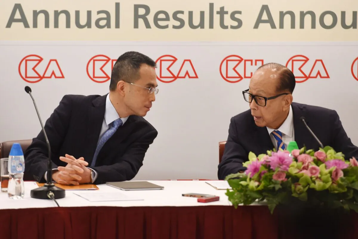 Li Ka-shing (R), founder of CK Hutchison and Hong Kong's richest man, speaks to his son Victor during a press conference in Hong Kong on March 16, 2018. (Anthony Wallace/AFP via Getty Images)