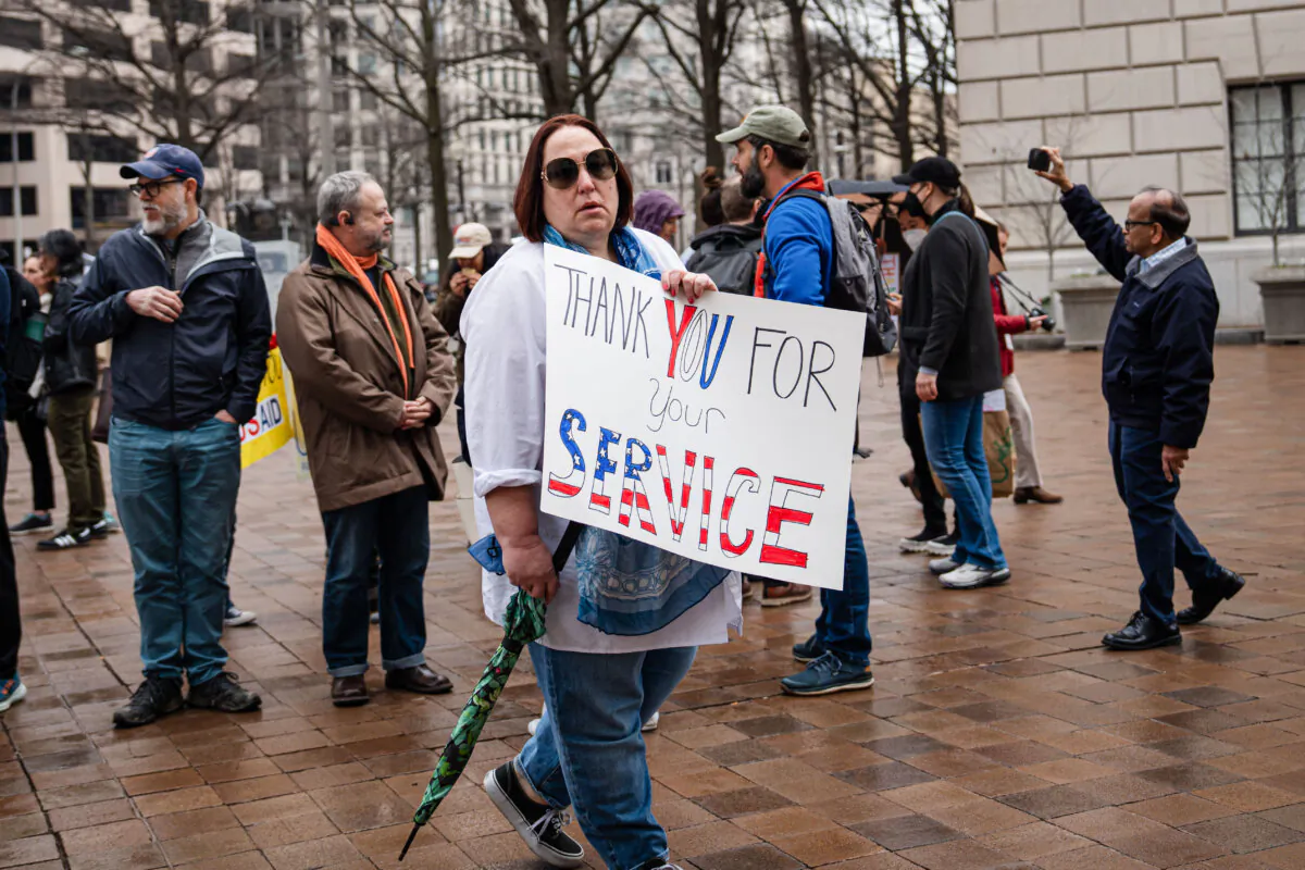 People stand outside in support of USAID employees leaving the building in Washington on Feb. 27, 2025. (Madalina Vasiliu/The Epoch Times)