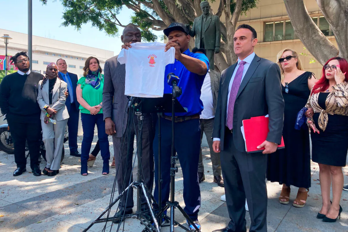 Jonathan Wright, 39, holds up the T-shirt he was given when he first went to MacLaren Children's Center in El Monte as an 8-year-old, during a news conference in Los Angeles, June 9, 2022. (Christopher Weber/AP Photo)