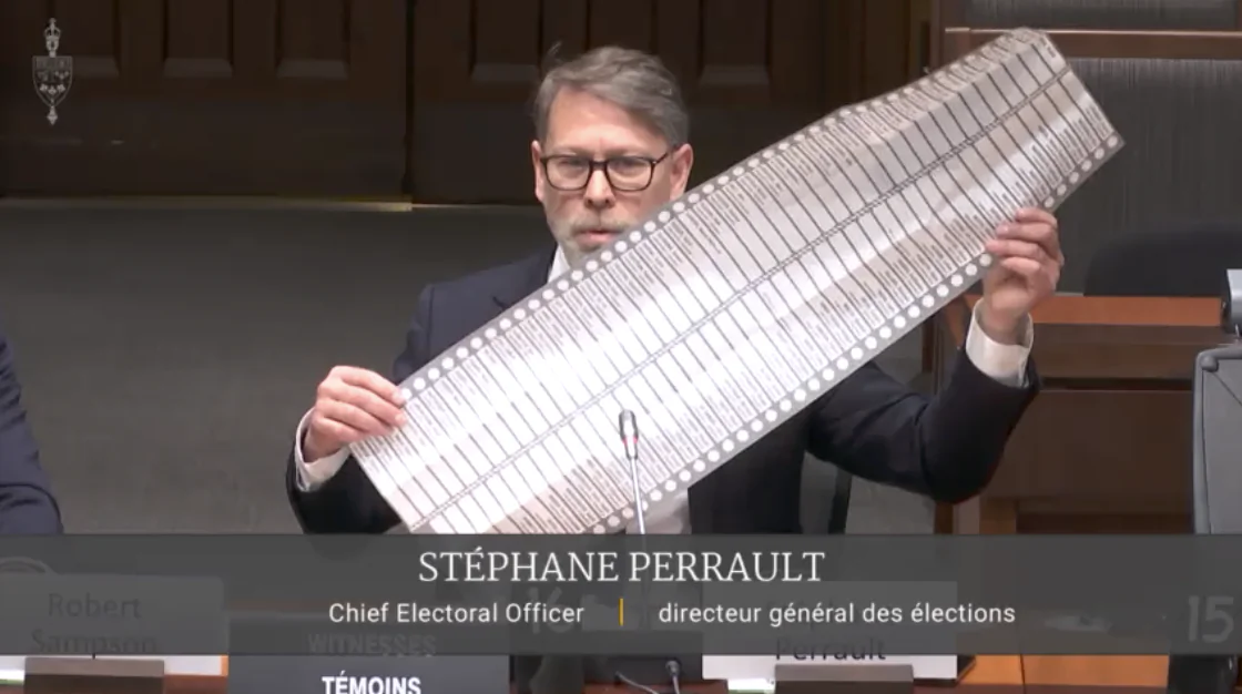 Chief Electoral Officer Stéphane Perrault displays a long ballot with 91 candidates used in a previous byelection during an appearance at a House of Commons committee on Nov. 21, 2024. (House of Commons/Screenshot via The Epoch Times)
