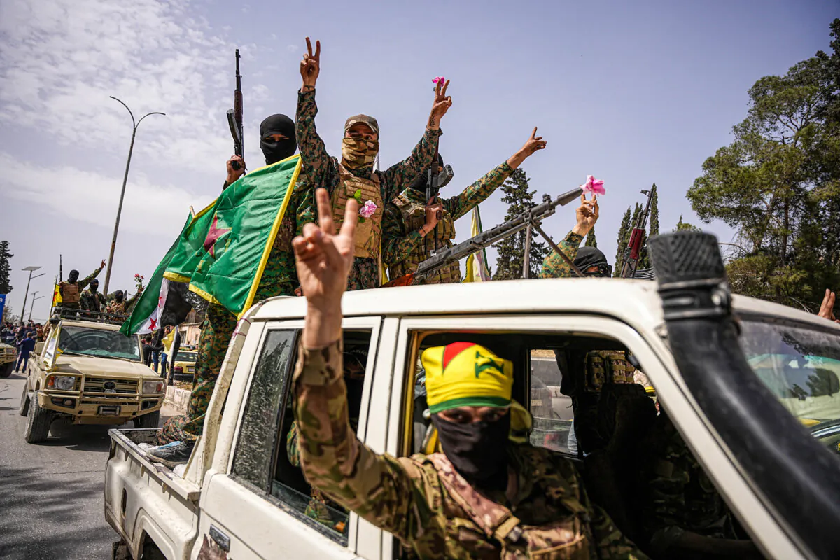 Kurdish-led Syrian Democratic Force fighters flash victory signs in a convoy leaving Aleppo, Syria, on April 9, 2025. (Mohamad Daboul/Middle East Images/AFP via Getty Images)