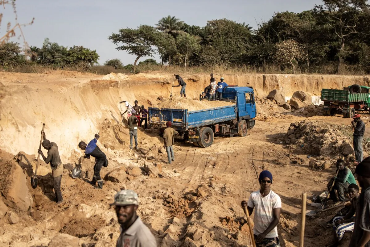 Artisanal sand miners shovel sand into trucks in an area destroyed by sand mining on the outskirts of Gunjur in The Gambia on Dec. 7, 2021. (John Wessels/AFP via Getty Images)