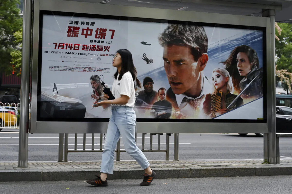 A woman walks past a poster for the movie "Mission Impossible—Dead Reckoning," at a bus stop in Beijing on July 21, 2023. (Greg Baker/AFP via Getty Images)