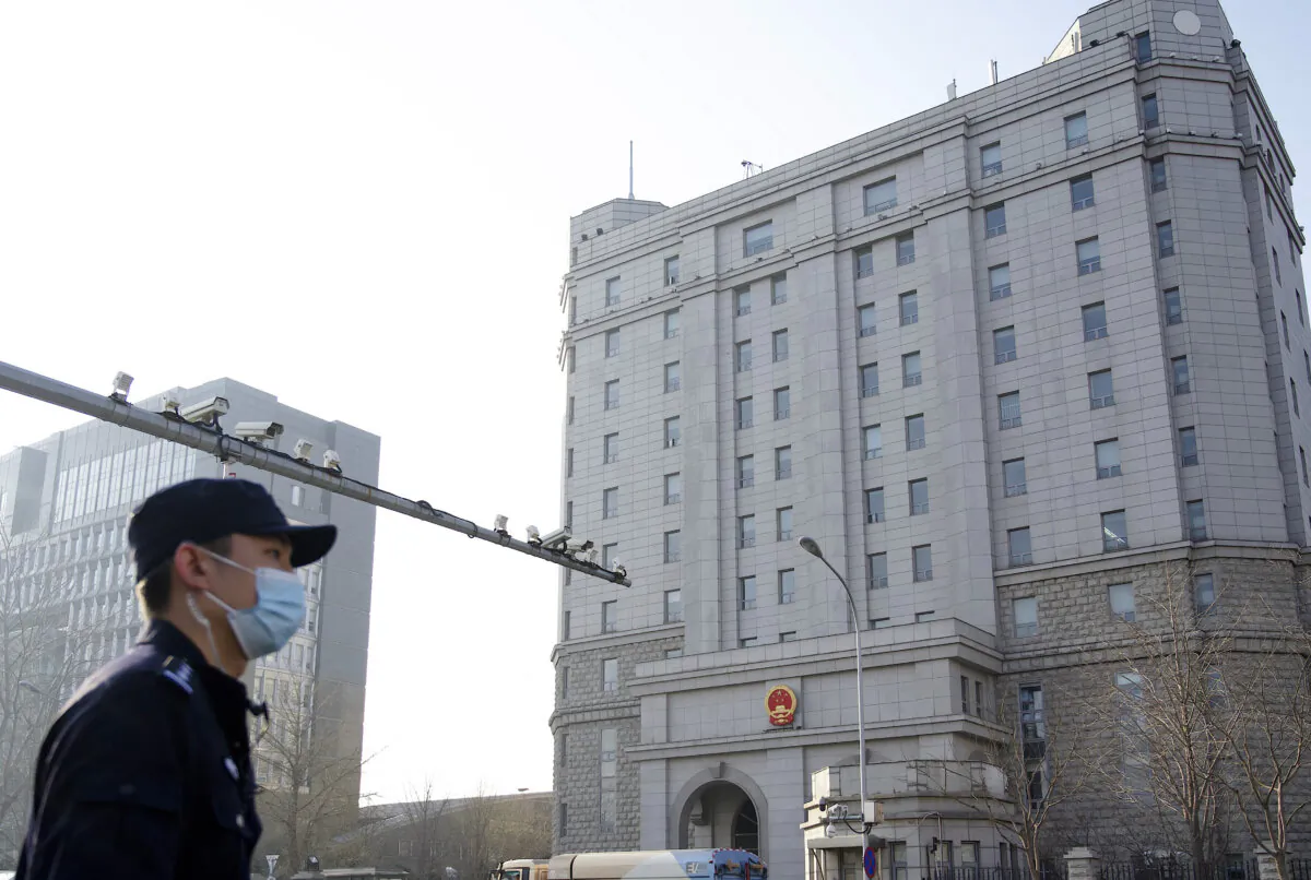 A policeman stands near a row of surveillance cameras in front of the Beijing No. 2 People's Intermediate Court in Beijing on March 31, 2022. (Noel Celis/AFP via Getty Images)