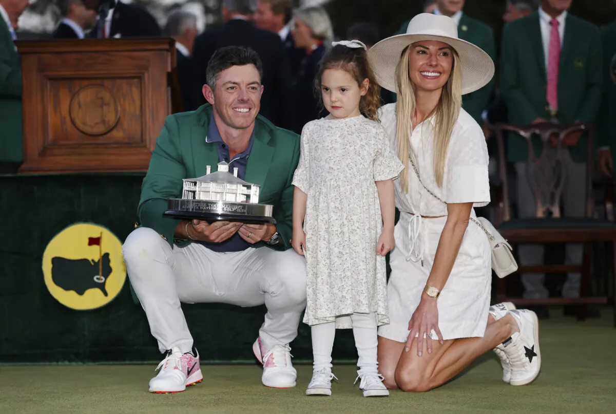 (L-R) Rory McIlroy of Northern Ireland poses with daughter Poppy and wife Erica Stoll while holding the Masters trophy during the Green Jacket Ceremony after winning the 2025 Masters Tournament at Augusta National Golf Club in Augusta, Georgia, on April 13, 2025. (Michael Reaves/Getty Images)