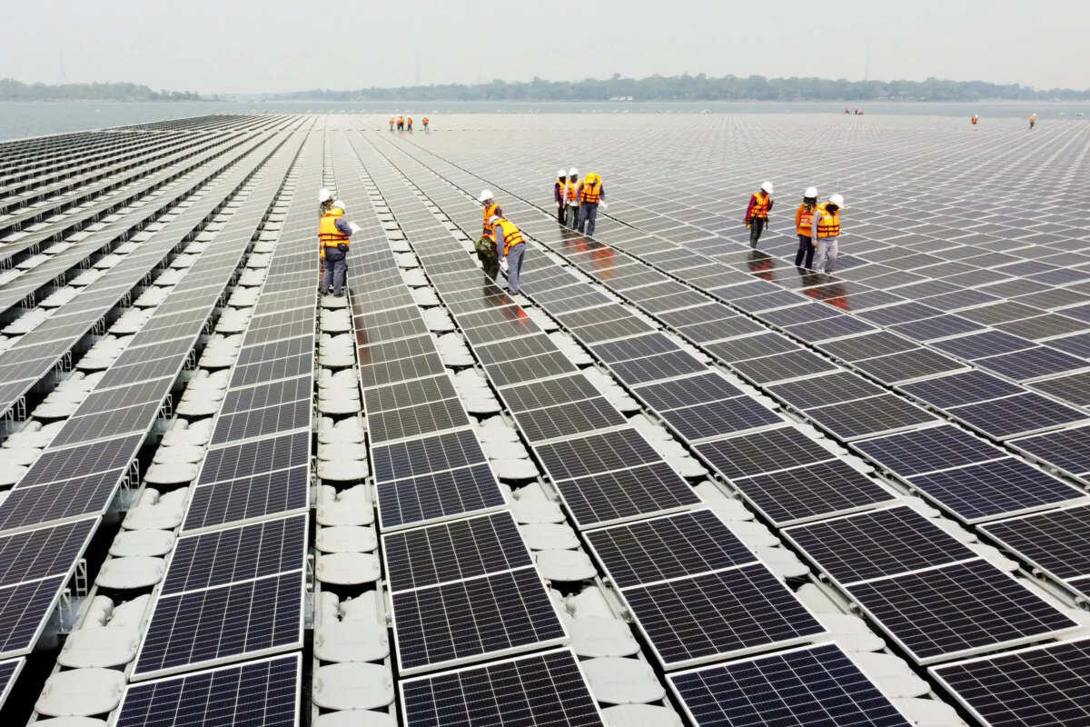 Workers walk between solar cell panels over the water surface of Sirindhorn Dam in Ubon Ratchathani, Thailand, on April 8, 2021. (Prapan Chankaew/Reuters)
