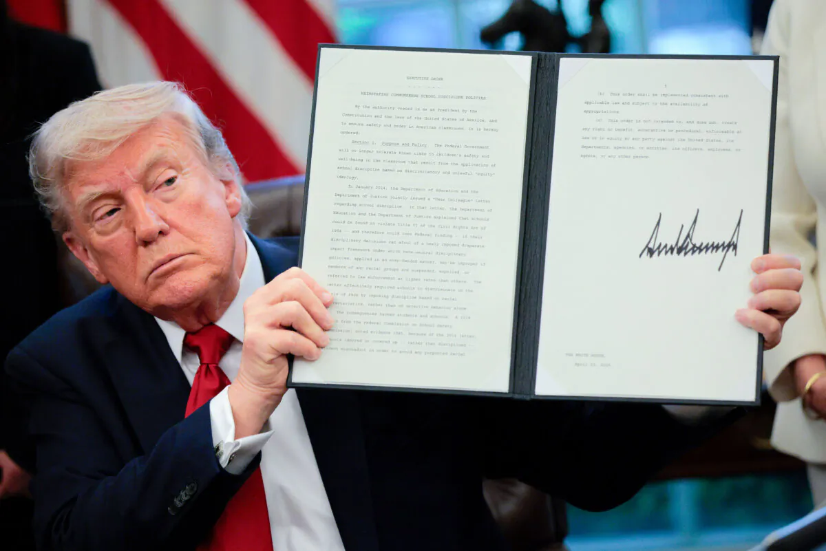 President Donald Trump displays a signed executive order titled "Reinstating Commonsense School Discipline Policies" in the Oval Office at the White House on April 23, 2025. (Chip Somodevilla/Getty Images)