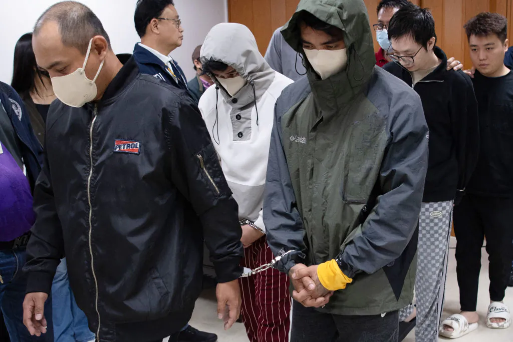 Chinese nationals (background R) and their alleged Filipino accomplices (L), arrested for alleged espionage, are escorted out of a room by National Bureau of Investigation agents after a news conference in Manila on Feb. 25, 2025. (Ted Aljibe/AFP via Getty Images)