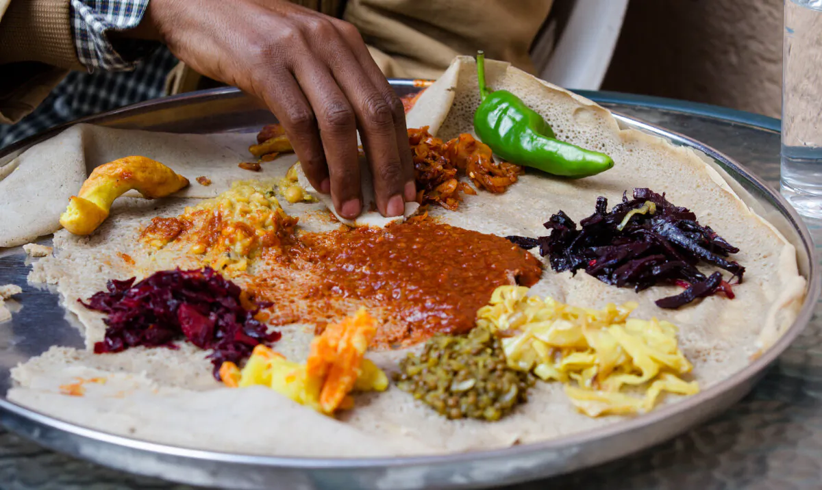 Injera, a fermented flatbread that's an important staple food in Ethiopia, is traditionally served as a bed for stews, meats, and vegetables—all eaten with the hands. (Andrzej Kubik/Shutterstock)
