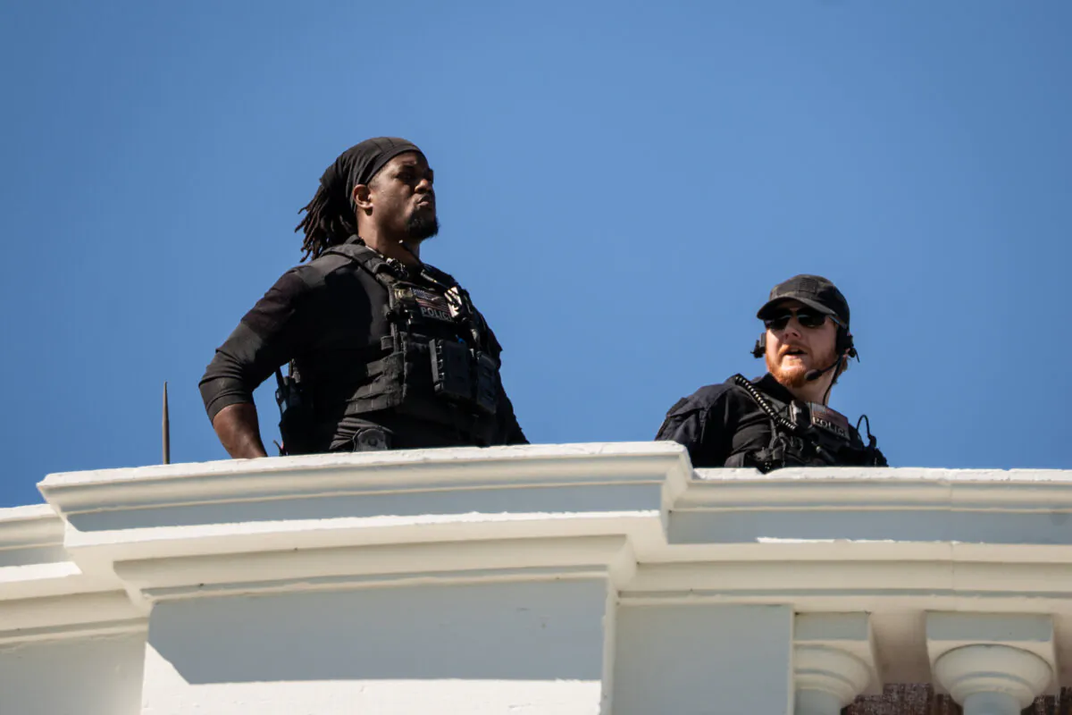 Two U.S. Secret Service special agents look out from the White House rooftop in Washington on April 28, 2025. (Madalina Vasiliu/The Epoch Times)