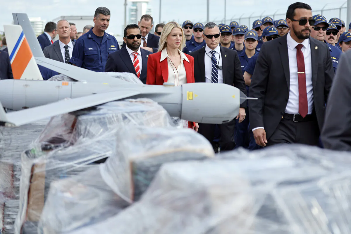 Attorney General Pam Bondi and FBI Director Kash Patel walk past pallets of shrink-wrapped narcotics and a drone used in the investigations as they arrive for a news conference at Port Everglades, Fla., on April 9, 2025. (Amy Beth Bennett /South Florida Sun-Sentinel via AP)