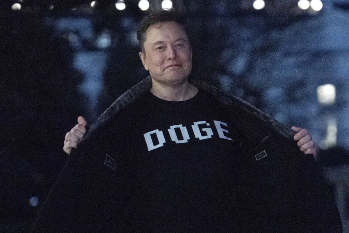 Elon Musk flashes his T-shirt that reads "DOGE" to reporters as he walks on the South Lawn of the White House on March 9, 2025. (Jose Luis Magana/AP Photo)
