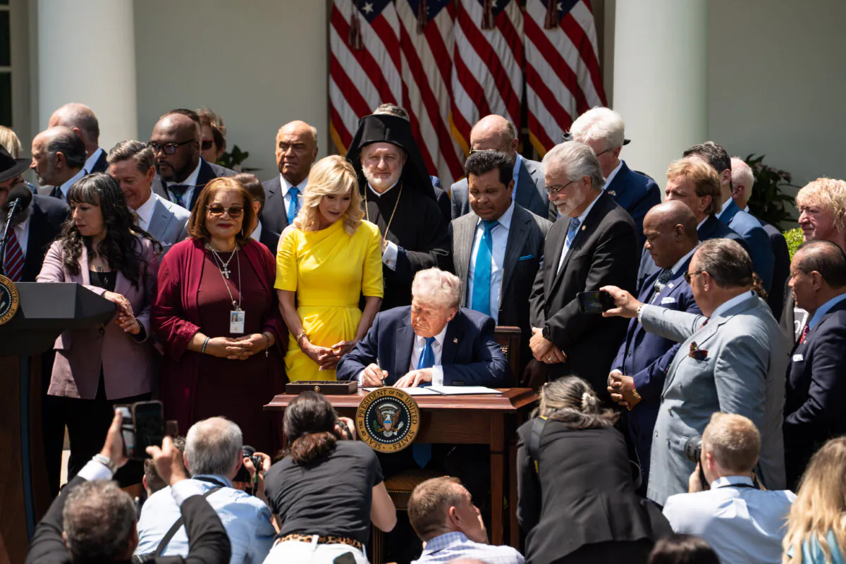 President Donald Trump signs an executive order establishing the Religious Liberty Commission during the National Day of Prayer event at the White House Rose Garden on May 1, 2025. (Madalina Vasiliu/The Epoch Times)