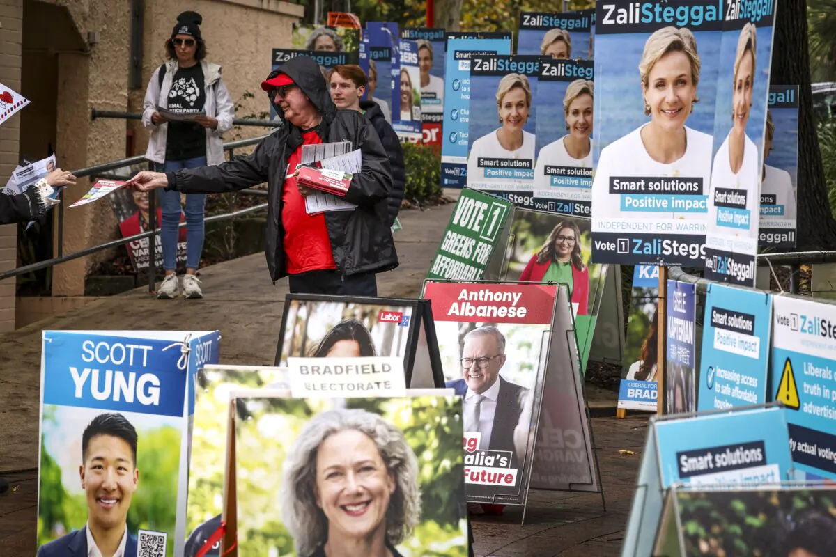 Volunteers hand out voting cards next to election candidate posters outside a pre-polling centre in Sydney on May 2, 2025. (David Gray/AFP via Getty Images)
