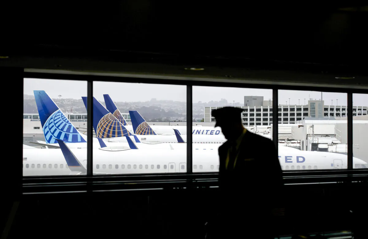 A pilot walks by United Airlines planes parked at gates at San Francisco International Airport in San Francisco on April 12, 2020. Despite President Donald Trump’s orders ending diversity, equity, and inclusion mandates, aviation insiders say these practices remain entrenched at airlines and could lead to unqualified pilots in the skies, raising safety concerns. (Justin Sullivan/Getty Images)