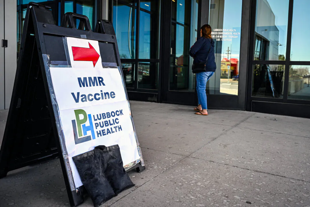 A person walks past a sign at a health center where the measles, mumps, rubella (MMR) vaccine is administered, in Lubbock, Texas, on Feb. 27, 2025. (Ronald Schemidt/AFP via Getty Images)