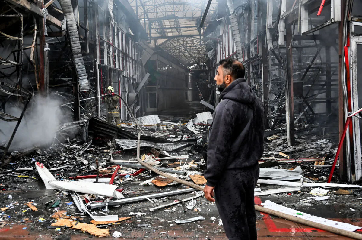 A man stands as a Ukrainian fireman finishes to put out a fire at the "Barabashovo" market following a drone strike in Kharkiv, Ukraine, on May 6, 2025. (Sergey Bobok/AFP via Getty Images)