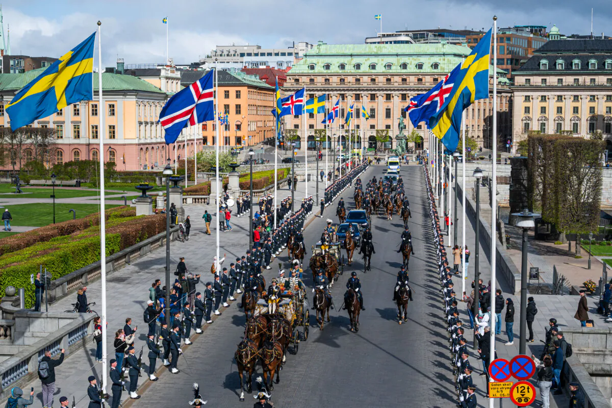 Swedish and Icelandic flags flutter on the roadside as King Carl XVI Gustaf of Sweden and Icelandic President Halla Tomasdottir arrive in a horse carriage procession to the Royal Palace in Stockholm on May 6, 2025. (Jonathan Nackstrand/AFP via Getty Images)