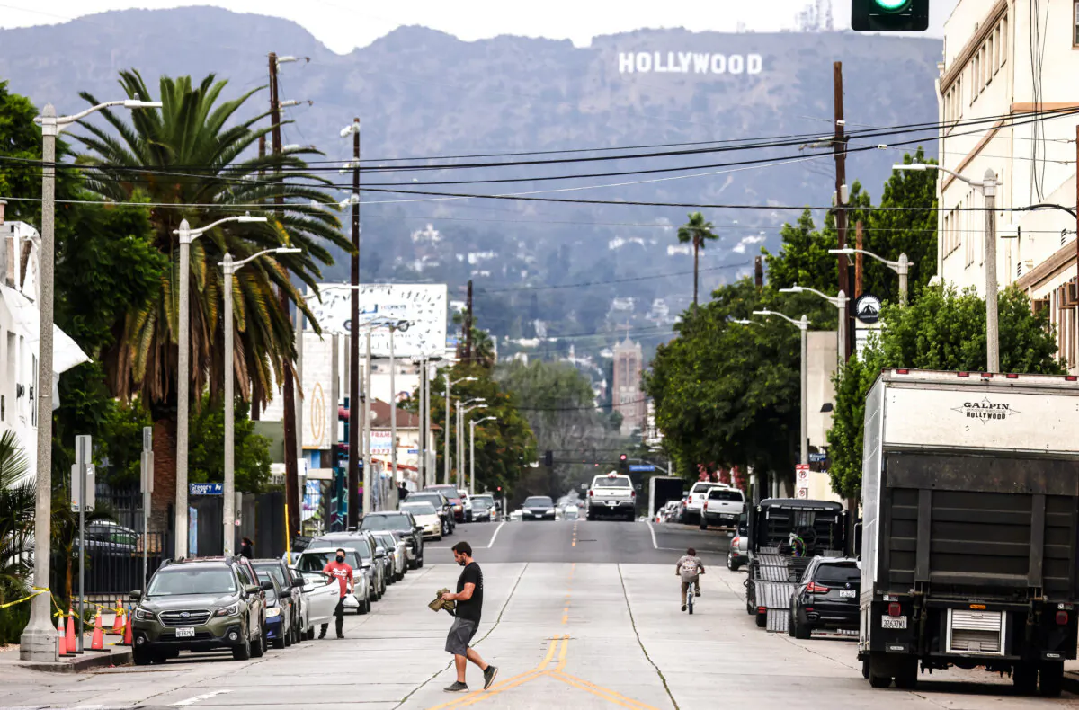 A pedestrian crosses a street in front of the Hollywood sign in Los Angeles on Oct. 7, 2021. (Mario Tama/Getty Images)