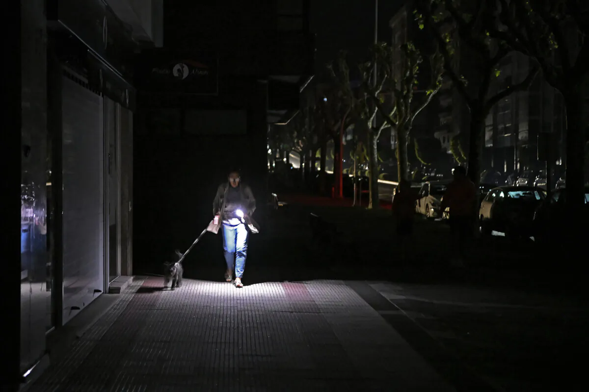 A woman uses her phone's flashlight while she walks her dog during a massive blackout affecting the entire Iberian Peninsula on April 28, 2025. (Miguel Riopa/AFP via Getty Images)