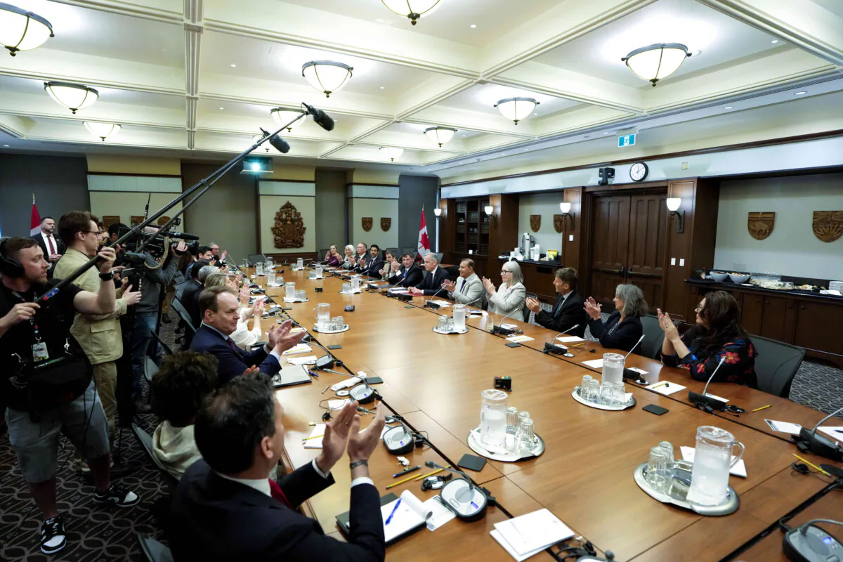 Ministers applaud after Prime Minister Mark Carney signs a document at the end of a meeting of the federal cabinet, in the West Block on Parliament Hill in Ottawa on May 14, 2025. (The Canadian Press/Justin Tang)