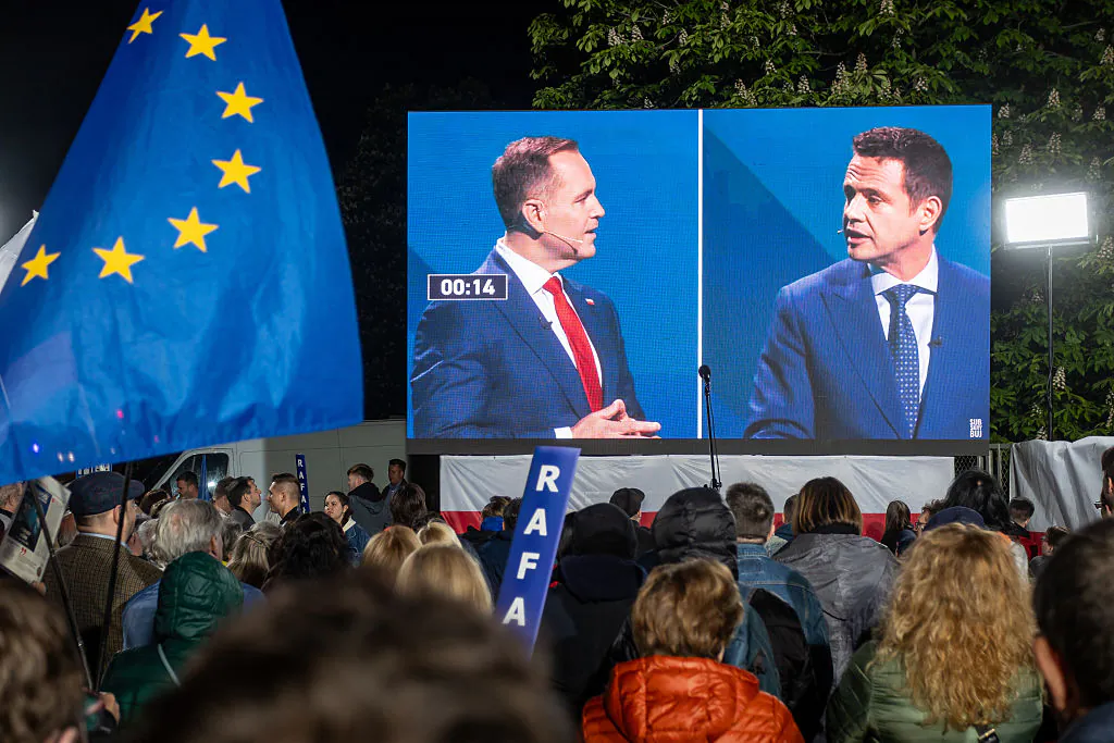 Supporters of Warsaw's mayor and member of Poland's ruling Civic Coalition party Rafal Trzaskowski (R) observe their presidential candidate debating his main opponent Karol Nawrocki (L) of the right-wing Law and Justice (PiS) party in front of the Polish National Television headquarters in Warsaw on May 12, 2025. (Wojtek Radwanski/AFP via Getty Images)