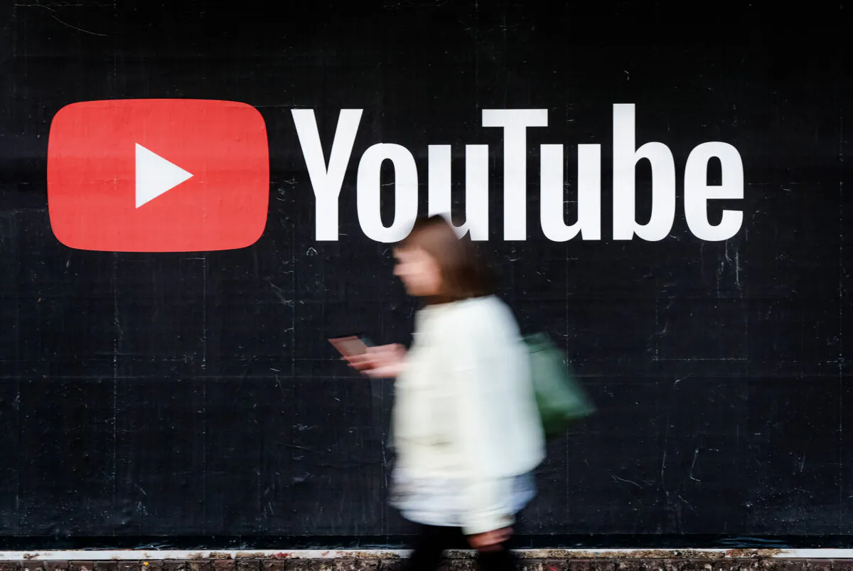 A woman with a smartphone walks past a billboard advertisement for YouTube in Berlin, Germany, on Sept. 27, 2019. (Sean Gallup/Getty Images)