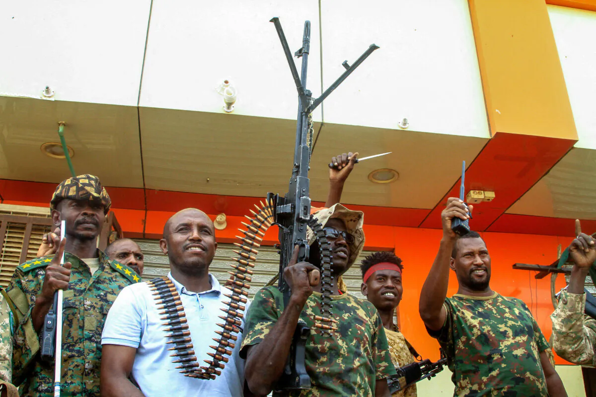 A man poses with Sudanese army soldiers in Salha, south of Omdurman, a day after recapturing it from the paramilitary Rapid Support Forces (RSF), on May 21, 2025. (Ebrahim Hamid/ AFP via Getty Images)