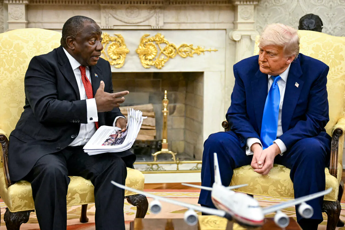 President Donald Trump hands papers to South African President Cyril Ramaphosa during a meeting in the Oval Office on May 21, 2025. (Jim Watson/AFP via Getty Images)
