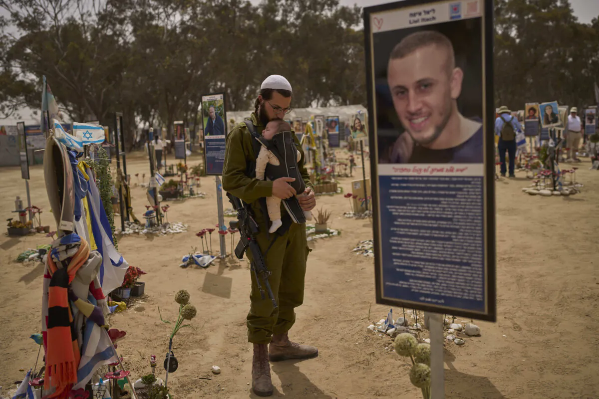 An Israeli soldier carries his child at the site of the Oct. 7, 2023, attack by Hamas-led terrorists at the Nova music festival near Kibbutz Reim in southern Israel, on April 30, 2025. (Ohad Zwigenberg/AP Photo)