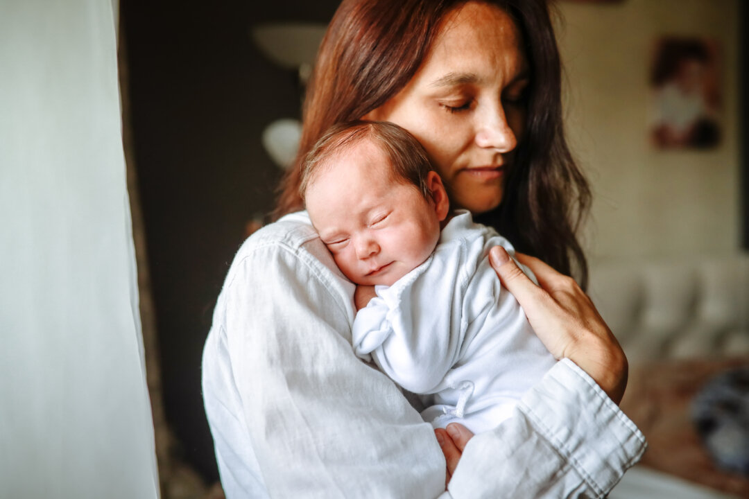 A mother rocks her newborn daughter on her shoulder at home. (Natalia Lebedinskaia/Getty Images)